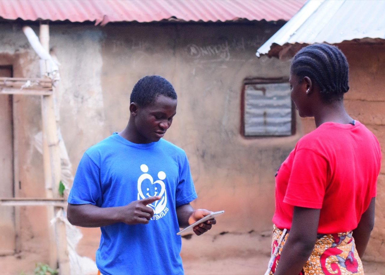 A Heartsmiles Consult field officer collecting survey data on a tablet.